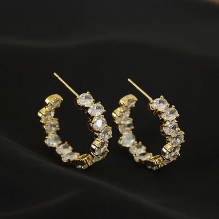 金のフープイヤリングの側面プロフィールで、曲線と宝石の配置を示しています。
