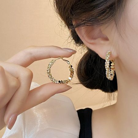 Close-up of a 14K gold-plated hoop earring with clear stones being worn.