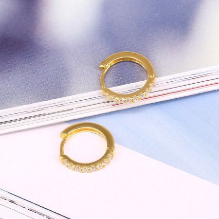 Vista dettagliata degli orecchini a cerchio in argento sterling placcato oro con pietre di zirconia trasparenti e scintillanti.