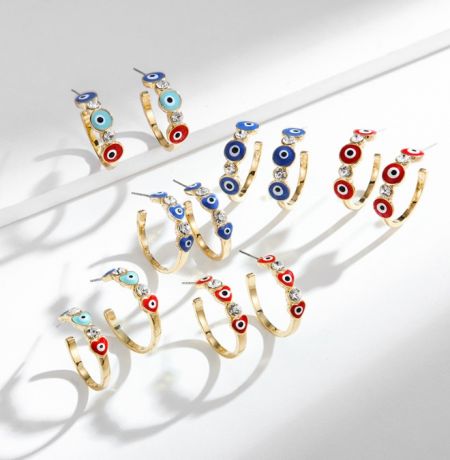 Una varietà di orecchini a cerchio dorati con smalti colorati e design dell'occhio di malocchio, parte della tendenza SS23.