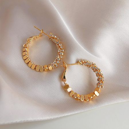 Detailed view of a gold hoop earring from the set, featuring intricate crystal embellishments.