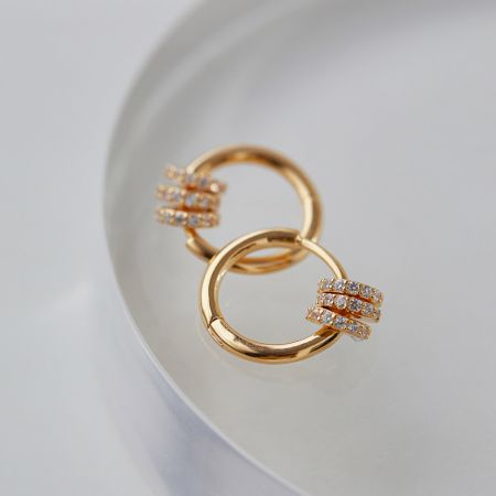 Otro ángulo de los pendientes de aro de oro que destaca los detalles con diamantes.