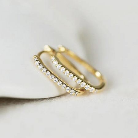 Vista dettagliata dell'orecchino huggie in oro che mostra i diamanti incastonati.