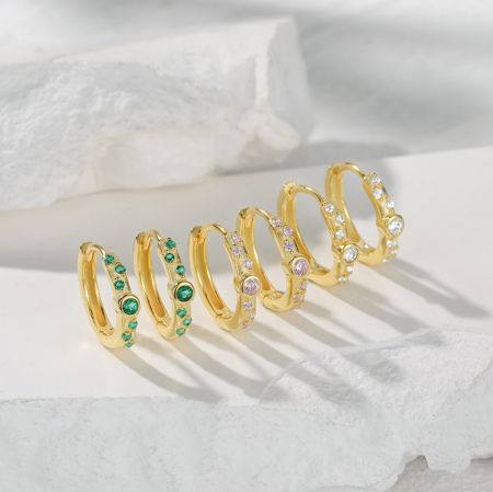 Una collezione di orecchini a cerchio in oro con varie decorazioni in pietre preziose, inclusi gli orecchini a cerchio CZ in evidenza.