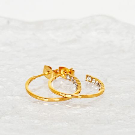 Close-up detail of the zirconia gemstones on the C-shape hoop earrings.
