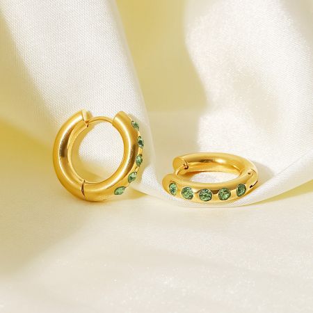 Close-up van de 20mm gouden creolen met levendige groene cubic zirconia stenen.