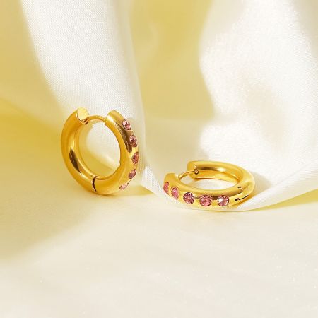 Gedetailleerd uitzicht op de gouden creolen die de sprankelende roze cubic zirconia tonen.