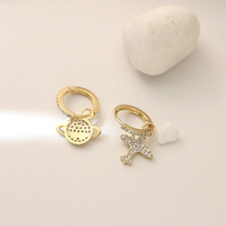 Vue complète des boucles d'oreilles en or avec des charms délicats de planète et d'étoile.