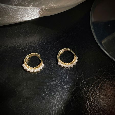 Detailed view of a pair of gold hoop earrings with delicate pearl accents.