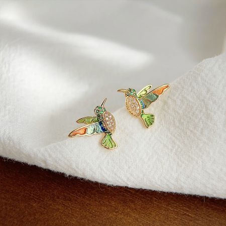 Front view of the gold hummingbird earrings highlighting the colorful enamel work on the wings and body.