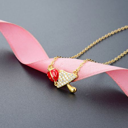 Eine verspielte vergoldete Sterlingsilber-Halskette mit einem Anhänger in Form einer Eistüte mit einem roten Kirschdetail.