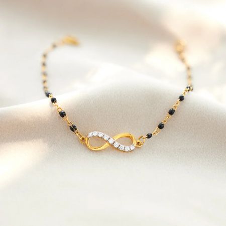 Conjunto de 5 pulseras de cuentas elegantes Infinidad de Esperanza - Primer plano de la pulsera Infinidad de Esperanza, exhibiendo el símbolo de infinito chapado en oro con piedras de circonio y elegantes cuentas negras en una cadena de plata esterlina 925.