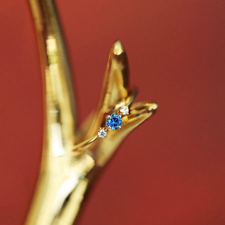 Schuin uitzicht op de elegante vergulde geboortesteenring op een neutrale achtergrond.