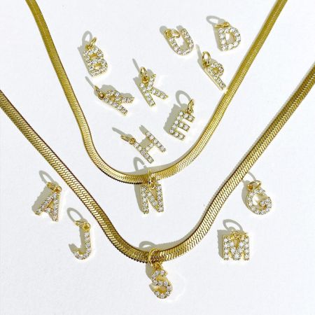 Een assortiment van gouden letterbedels en kettingen, die de productvariëteit benadrukken.