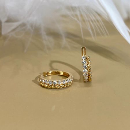 Un paio di orecchini huggie a cerchio con perline CZ in argento sterling 925, placcati in oro 18k, mostrati su uno sfondo pulito.