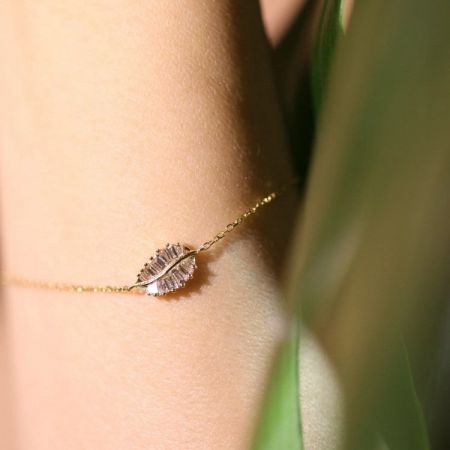 925 Sterling Zilver 14K Vergulde Cubic Zirconia Bladarmband - Een close-up van een elegante 14K vergulde sterling zilveren armband met een bladvormige hanger bezet met sprankelende cubic zirconia stenen.