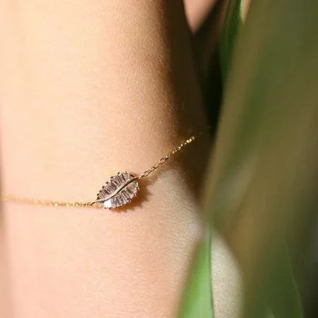 925 Sterling Zilver 14K Vergulde Cubic Zirconia Bladarmband - Een close-up van een elegante 14K vergulde sterling zilveren armband met een bladvormige hanger bezet met sprankelende cubic zirconia stenen.