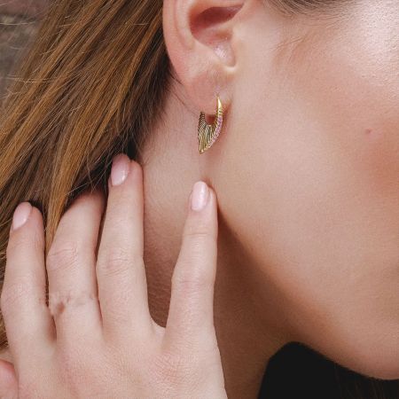 Modello che mostra l'orecchino a foglia dorato con delicati gemme rosa.