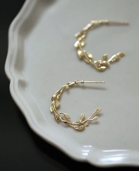 Vista laterale dettagliata dell'orecchino a cerchio fogliare in argento sterling 925, evidenziando i dettagli in zirconia cubica e la texture della placcatura in oro.