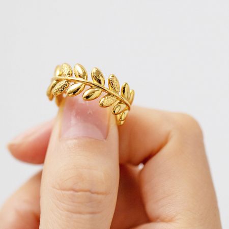 Detailed studio shot of the stainless steel olive branch leaf ring in gold.