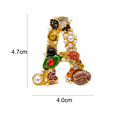 Primer plano del broche de la letra 'A' barroca, destacando los intrincados detalles de strass y perlas.