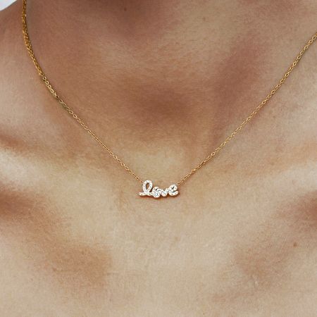Juego de 5 collares de amor delicados en oro con colgante de circonita cúbica en acero inoxidable - Modelo usando un delicado collar de amor de oro con un colgante de circonita cúbica brillante, fabricado en acero inoxidable anti-deslustre. Perfecto para regalar en el Día de San Valentín.