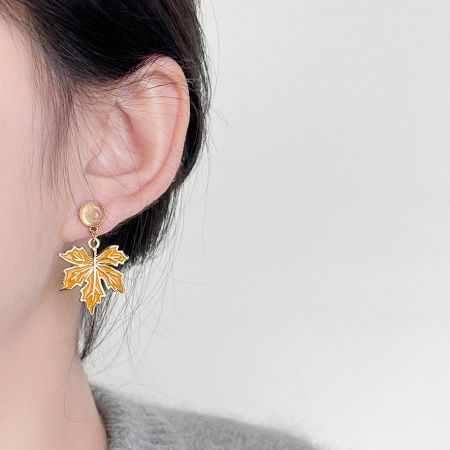 Visão detalhada do brinco em forma de folha de bordo banhado a ouro, destacando seu design intricado.