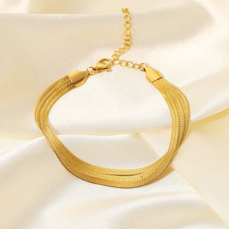 El conjunto de 5 pulseras de oro exhibido sobre un lujoso fondo de satén crema.
