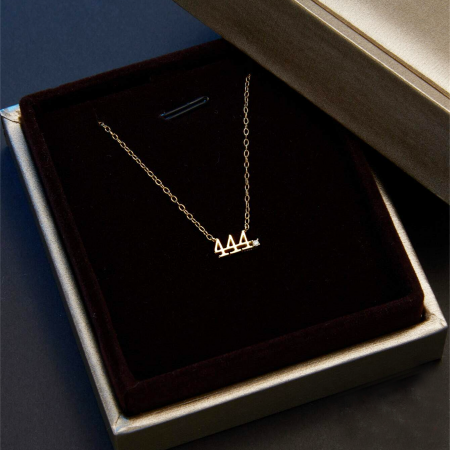 Collana con numero angelico 444 placcata in oro esposta in una scatola di gioielli.
