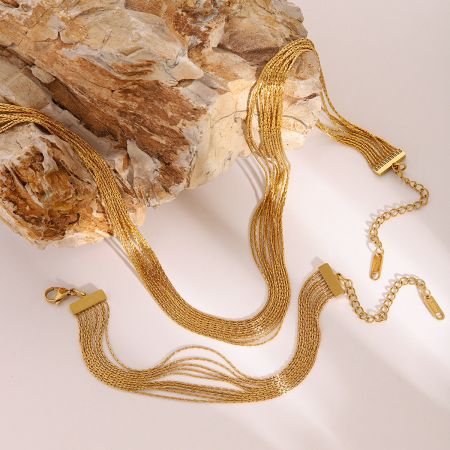 Gouden gelaagde ketting en armbandset, stapelbare sieraden van roestvrij staal voor meisjes, set van 5. - Een stijlvolle gouden gelaagde ketting en armbandset gemaakt van roestvrij staal, weergegeven op een neutrale beige achtergrond.