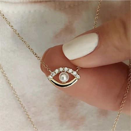 Detailed view of the gold evil eye pendant with its pearl and sparkling zircons.
