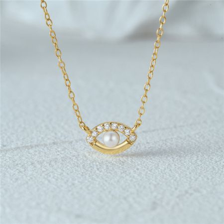 Collar de ojo malvado de zirconia con perla de plata esterlina 925 - Un primer plano de un collar con ojo malvado de plata esterlina 925 en acabado dorado, con una perla central y piedras de circonita alrededor.