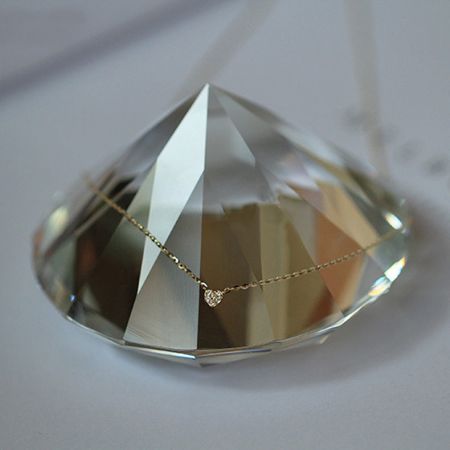 The gold heart pendant necklace elegantly displayed on a crystal, emphasizing its luxurious quality.