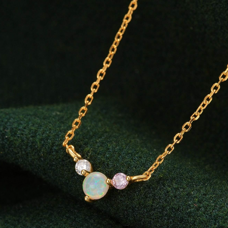 A stylish gold necklace from the set with a trio of opal, pink, and white gemstones.