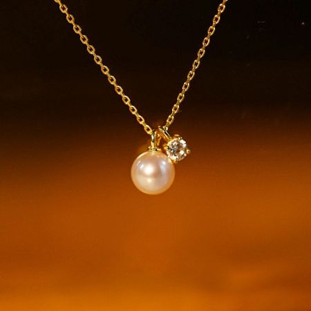 Detalhe do pingente de pérola e zircônia na corrente de ouro.