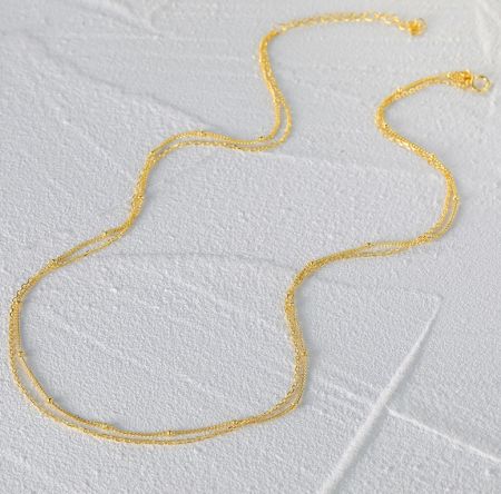 Primer plano del collar de cadena chapado en oro contra un fondo blanco