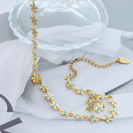 La lunghezza completa della collana dorata con delicati charm a forma di fiore turchesi disposti.