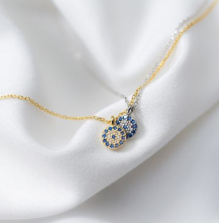 Collar con colgante del Ojo Maligno de plata esterlina 925 - Un primer plano del collar con colgante del Ojo Maligno de plata esterlina 925 en acabado dorado, con un colgante circular que presenta piedras de circonita cúbica azul y blanca que brillan.