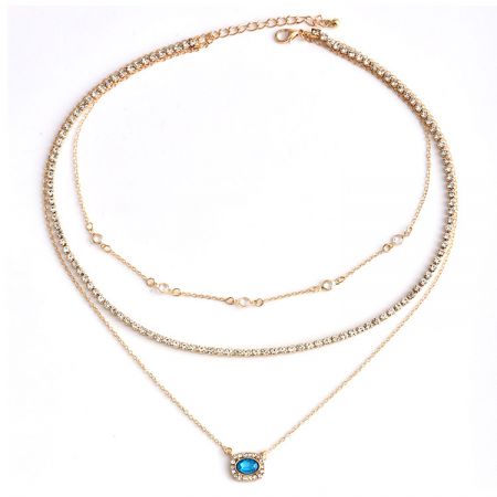 Detailed view of the blue gemstone pendant on the gold-toned chain.