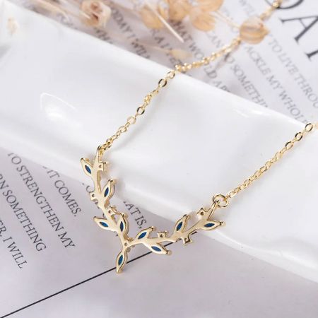 Una vista minimalista del collar de oro enfocándose en la simple elegancia del colgante de hoja azul.