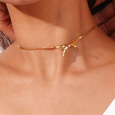 Collar choker de cadena de serpiente plana dorada de acero inoxidable, juego de 5 - Una mujer usando el elegante collar choker de cadena de serpiente plana dorada con un delicado colgante de lazo, mostrando su diseño sofisticado y acabado en oro de 18k.