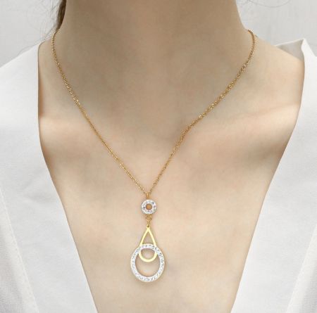 Primer plano del collar de oro con un colgante de círculo entrelazado adornado con cristales transparentes.