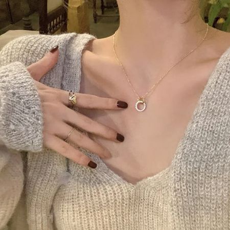 A close-up view of the zircon double-circle pendant on the gold necklace.