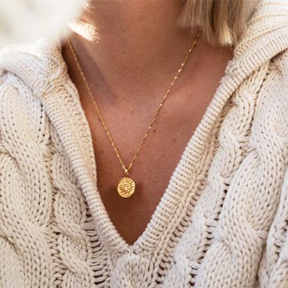 Collar con colgante de moneda dorada de sol en plata esterlina 925 - Un modelo que lleva el collar con colgante de moneda dorada de sol en plata esterlina 925, mostrando su elegante caída y diseño contra un suéter crema.