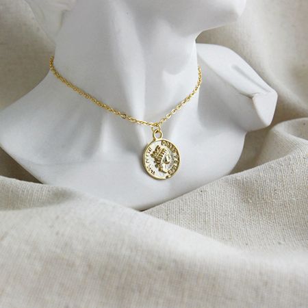 Gros plan du collier ras du cou en pièce de monnaie vintage en or, mettant en valeur le profil détaillé d'Élisabeth.