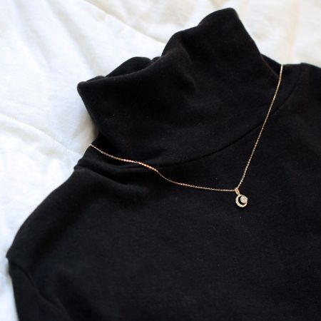 Un modello che indossa una collana con pendente d'oro, dimostrando lo stile e la lunghezza.