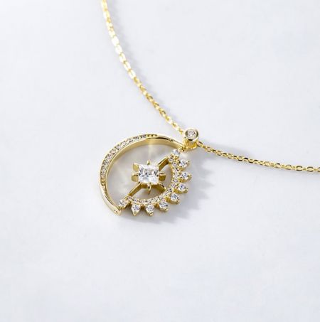 El collar de luna y estrella pavimentado de plata esterlina 925 mostrado en un lujoso acabado dorado.