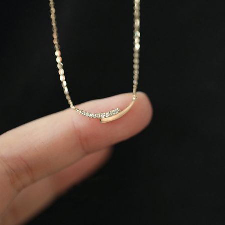 A unique curved pendant necklace with small diamonds, part of the 925 silver set.