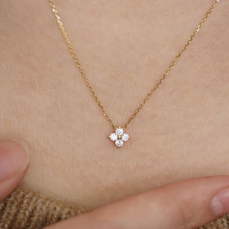Detailed view of the sparkling zircon stones on the four-leaf flower charm.