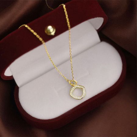 Collar de oro con un colgante de diamante en una caja de regalo de terciopelo rojo.